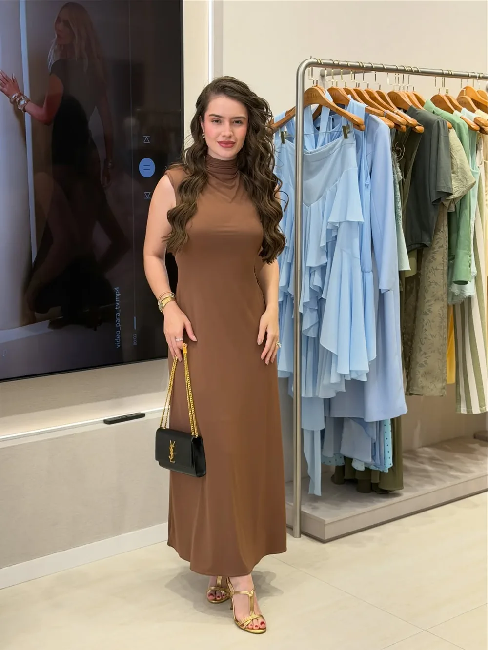 Júlia Cardoso dentro da loja Dona Laurinda, com araras de roupas ao fundo
